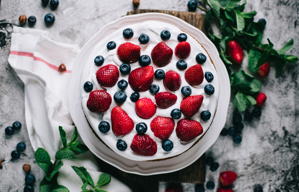 A cake topped with whipped cream and fresh berries 