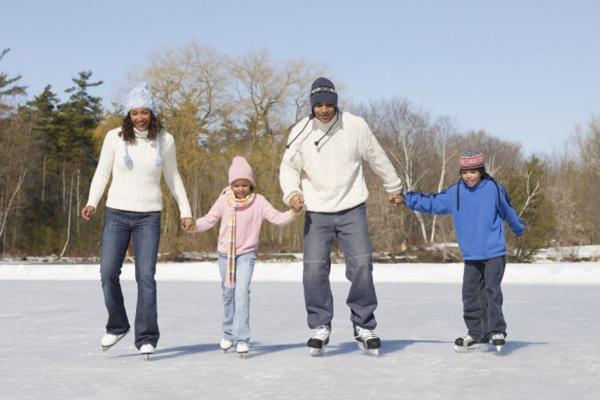 Family of 4 skating on an outdoor pond