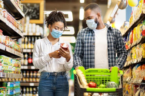 Woman and man looking at food labels in a grocery store wearing masks