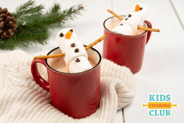 Marshmallow snowman laying on top of a mug of hot chocolate