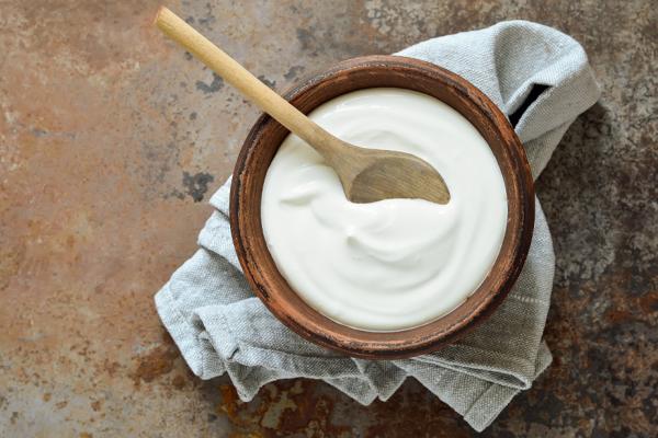 Yogurt in wooden bowl with wooden spoon 