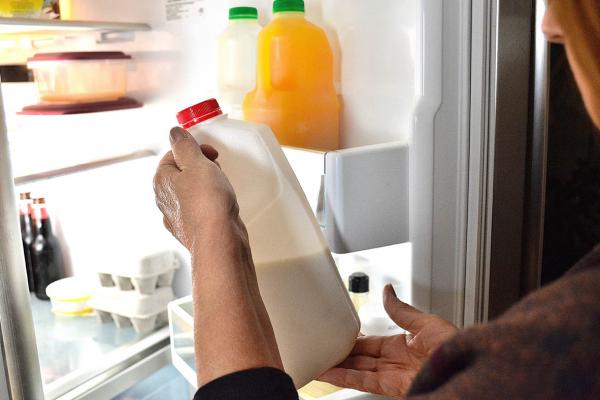 Woman retrieves a bottle of frozen milk from the refrigerator, depicting good food storage practice