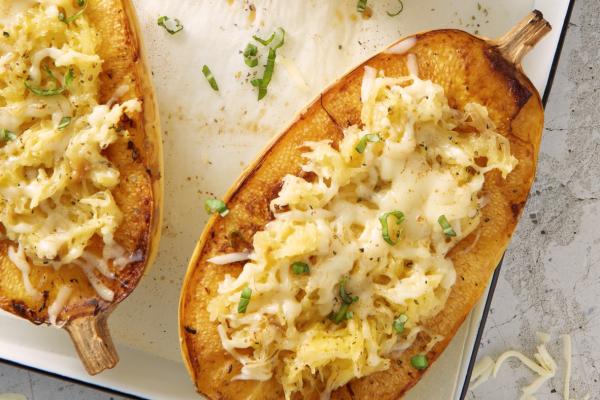 Oven-baked spaghetti squash boats topped with melted Mozzarella and herbs on a ceramic dish