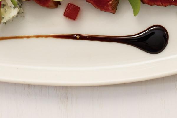 Thick and glossy balsamic glaze drizzled over a dish