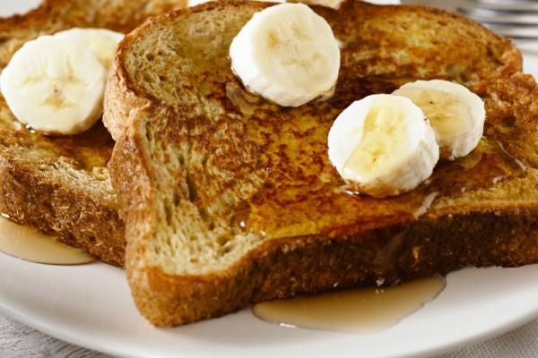 Plate of french toast topped with sliced bananas and syrup