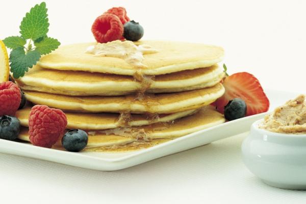 Stacked pancakes with berries, drizzled with Canadian cinnamon spread and extra serving to the side