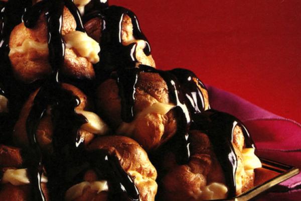 Stack of profiterole cream puffs covered in chocolate sauce