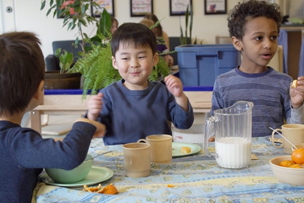 Three boys sitting around a table eating a snack