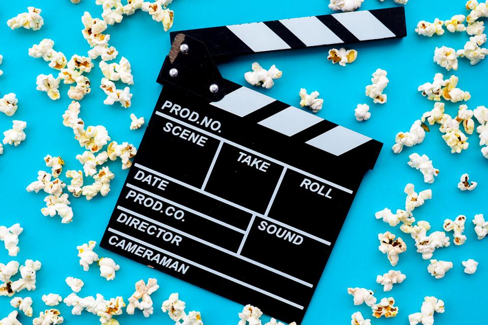 A movie clapperboard surrounded by popcorn