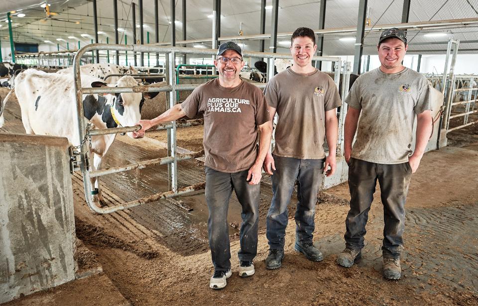 A family of Canadian Dairy Farmers with their cows in a barn
