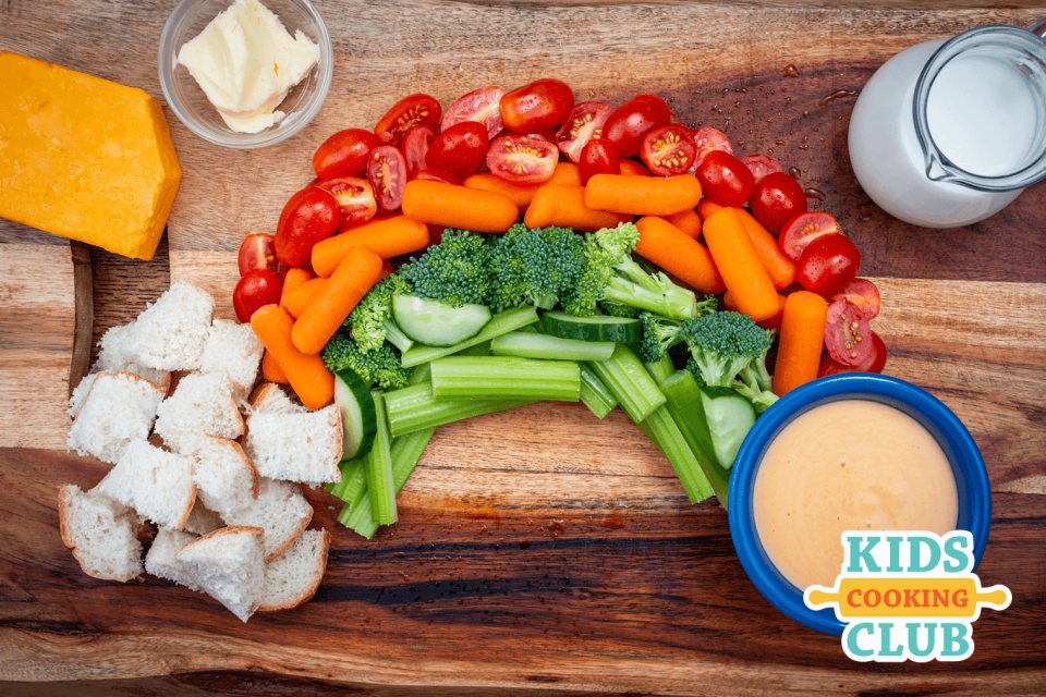 Cheese sauce in a bowl served with bread and raw veggies on a wooden cutting board
