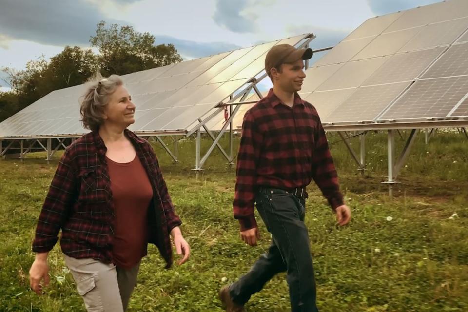 Farmers walking in front of their solar panels