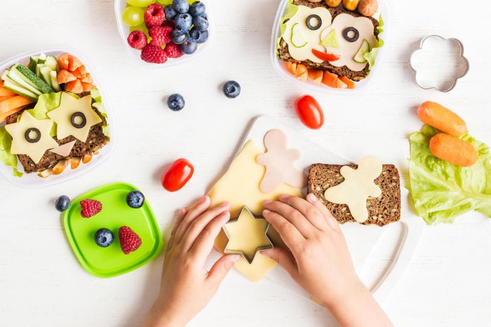 Child's hands using a cookie cutter to make shapes in cheese