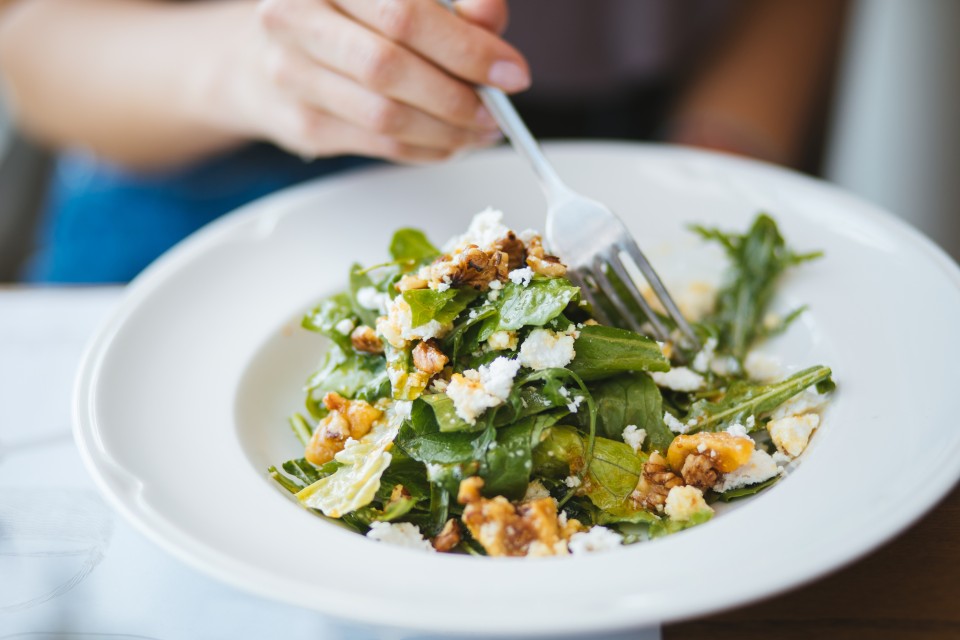 A person enjoying a salad topped with cheese 