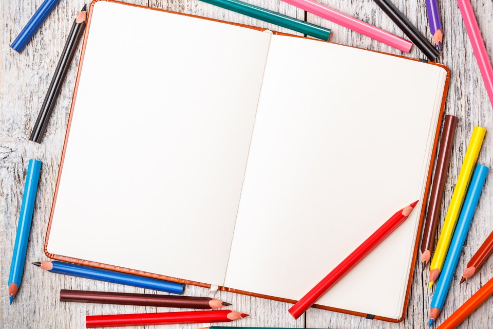 open blank booklet with colored pencils