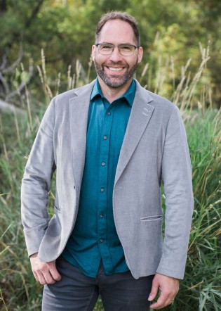 Kenton standing in a field with grass and trees