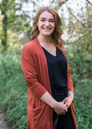 Picture of Mary standing with shrubs in the background
