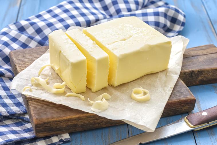 Sliced butter on wooden board placed on a blue and white checkered tablecloth