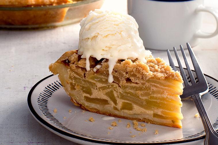 Slice of sour cream apple pie with melting ice cream on top, a classic dessert with a twist