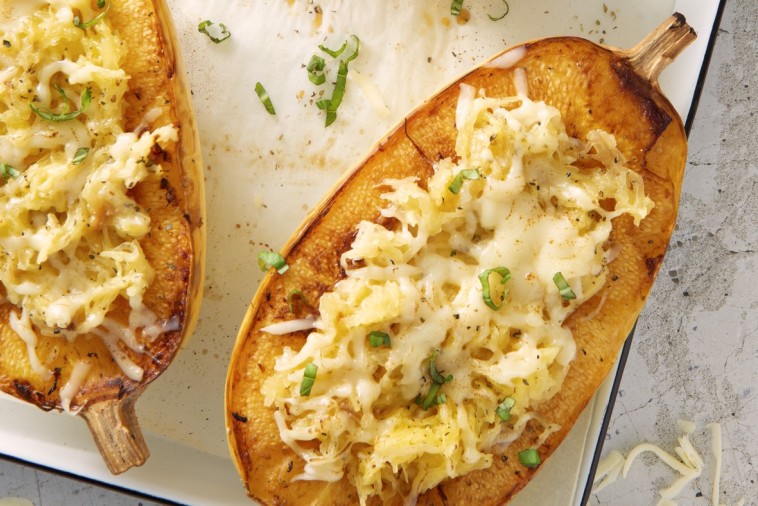 Oven-baked spaghetti squash boats topped with melted Mozzarella and herbs on a ceramic dish