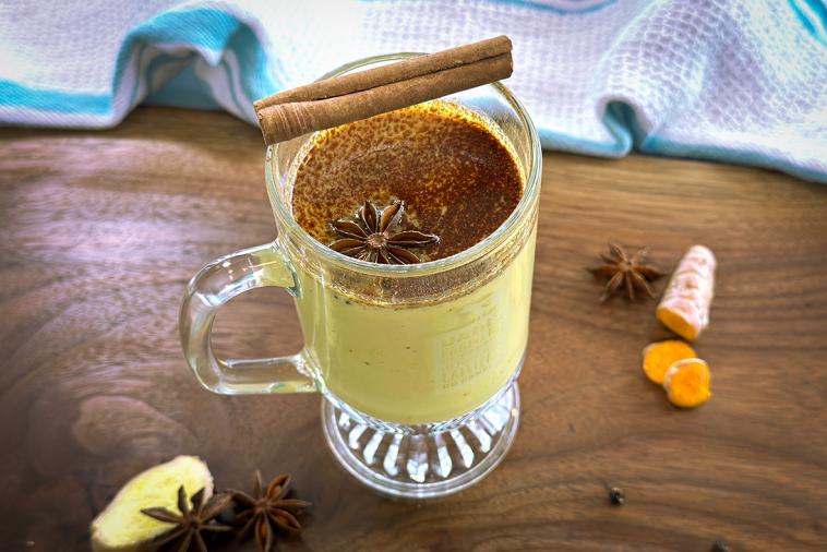 Warm Canadian Golden Milk served in a cup, garnished with a cinnamon stick on top