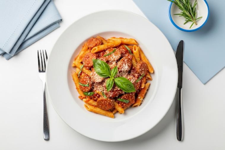 Top down image of a plated dish of penne and sausage