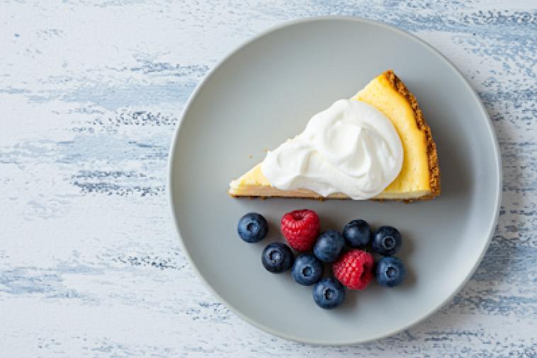 Top down image of a plate of cheesecake with mixed berries to the side