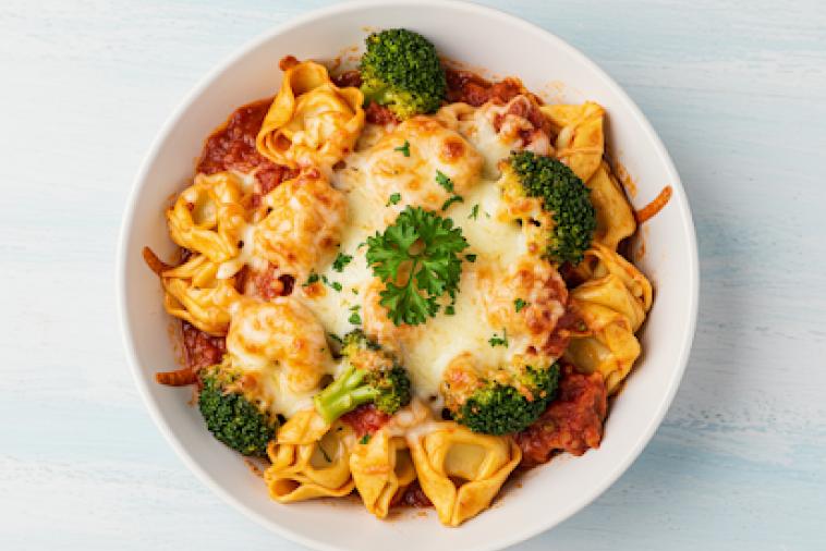 Top down image of a bowl of tortellini caserole with baked cheese