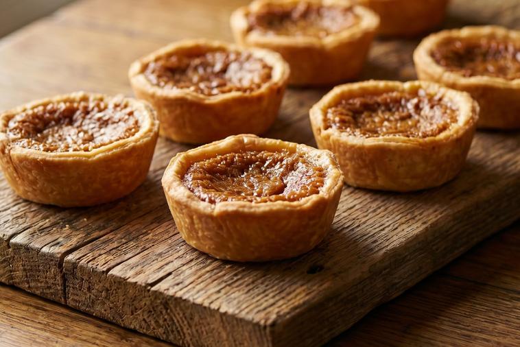 Golden brown butter tarts cooling on a wire rack, showcasing their flaky crust and caramelized filling