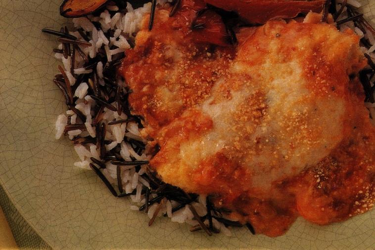 Succulent Chicken Parmesan with a crispy golden coating, smothered in tomato sauce, atop a bed of wild rice blend