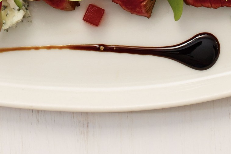 Thick and glossy balsamic glaze drizzled over a dish