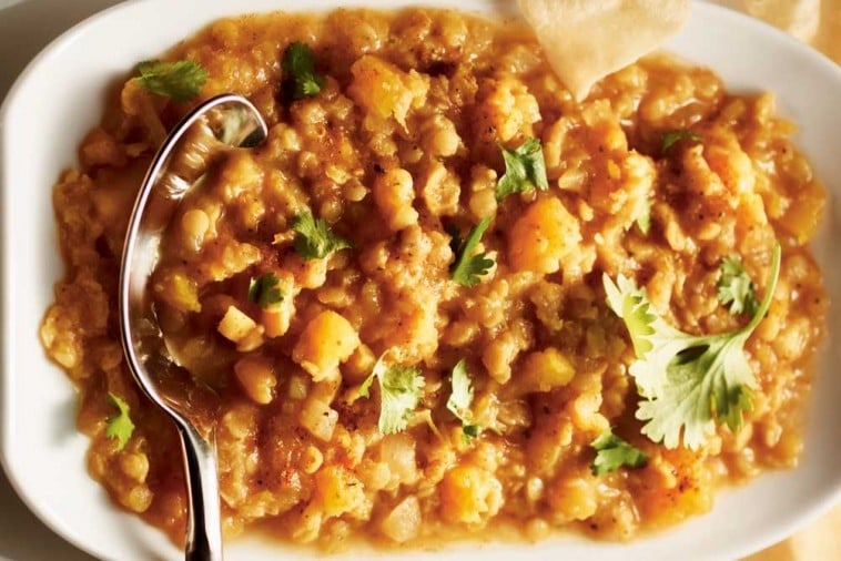 A comforting bowl of butternut squash dal garnished with fresh cilantro, accompanied by a piece of flatbread, ready for a wholesome meal.