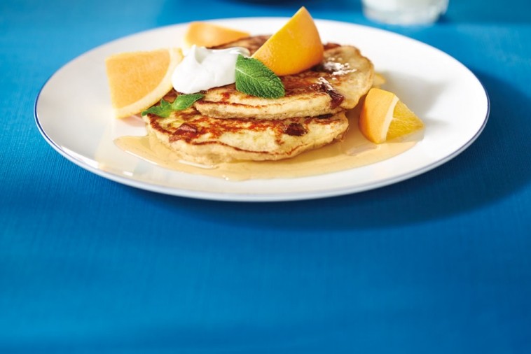 Plate of pancakes covered in syrup and fruit