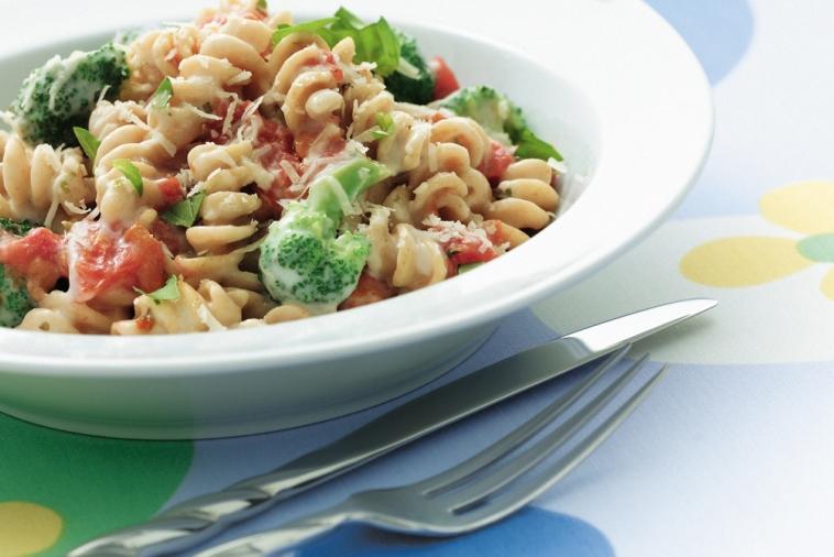 Bowl of parmesan rotini pasta with tomatoes and broccoli