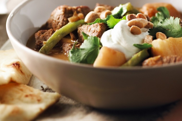 slow cooker beef potato curry Bowl of beef curry topped with yogurt and served with naan