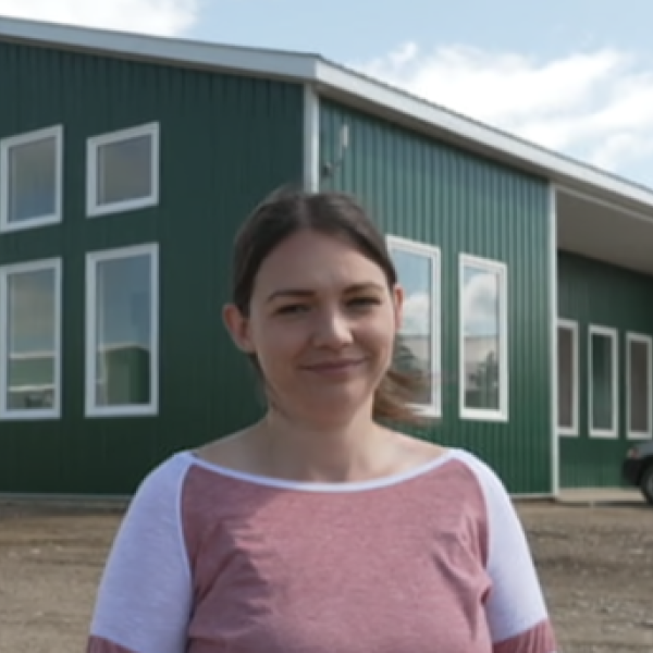 Woman outside farm building.